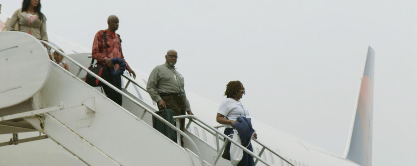 Čtyři lidé vystupují z letadla, schází po přistavených schodech.