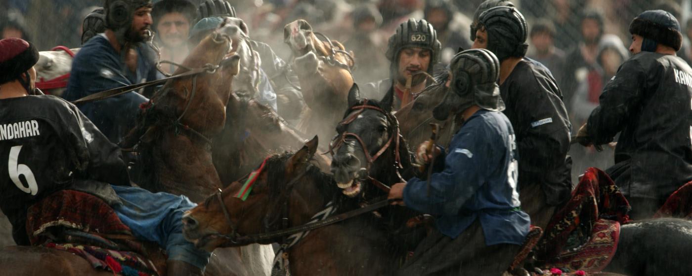 Skupina mužů ve sportovním oblečení a helmách na koních.