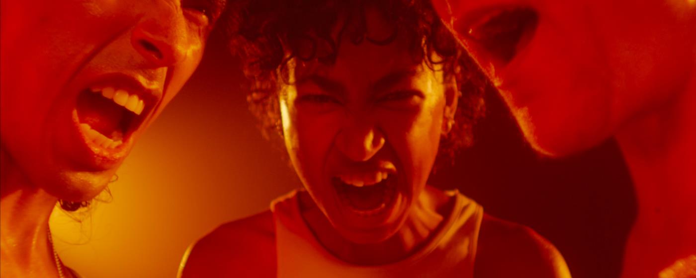 Three people yelling in a red-tinted light.