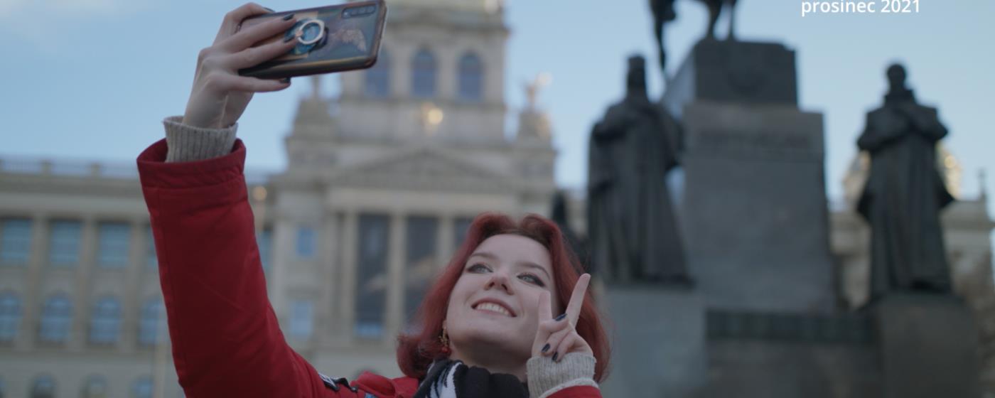 Žena fotí selfie před budovou Národního muzea, text na fotce 