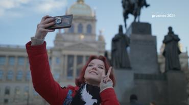 Woman taking a selfie with statues and a dome building in background.