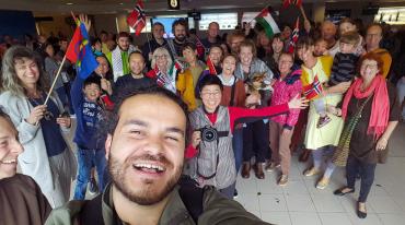 Skupina lidí se směje na selfie s vlajkami různých zemí.