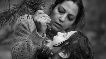 Woman feeding child water from a pine tree branch, monochrome image.