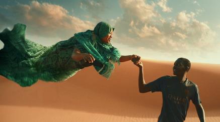 Chlapec kráčící pouští drží ruku ženy, která se vznáší vzduchem. 
