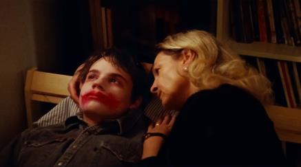 Woman comforting boy with red residue on his face.