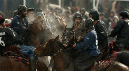 Men in helmets on horses playing a traditional game.