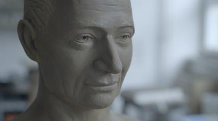 Detailní socha mužské hlavy z hlíny s realistickými rysy obličeje.